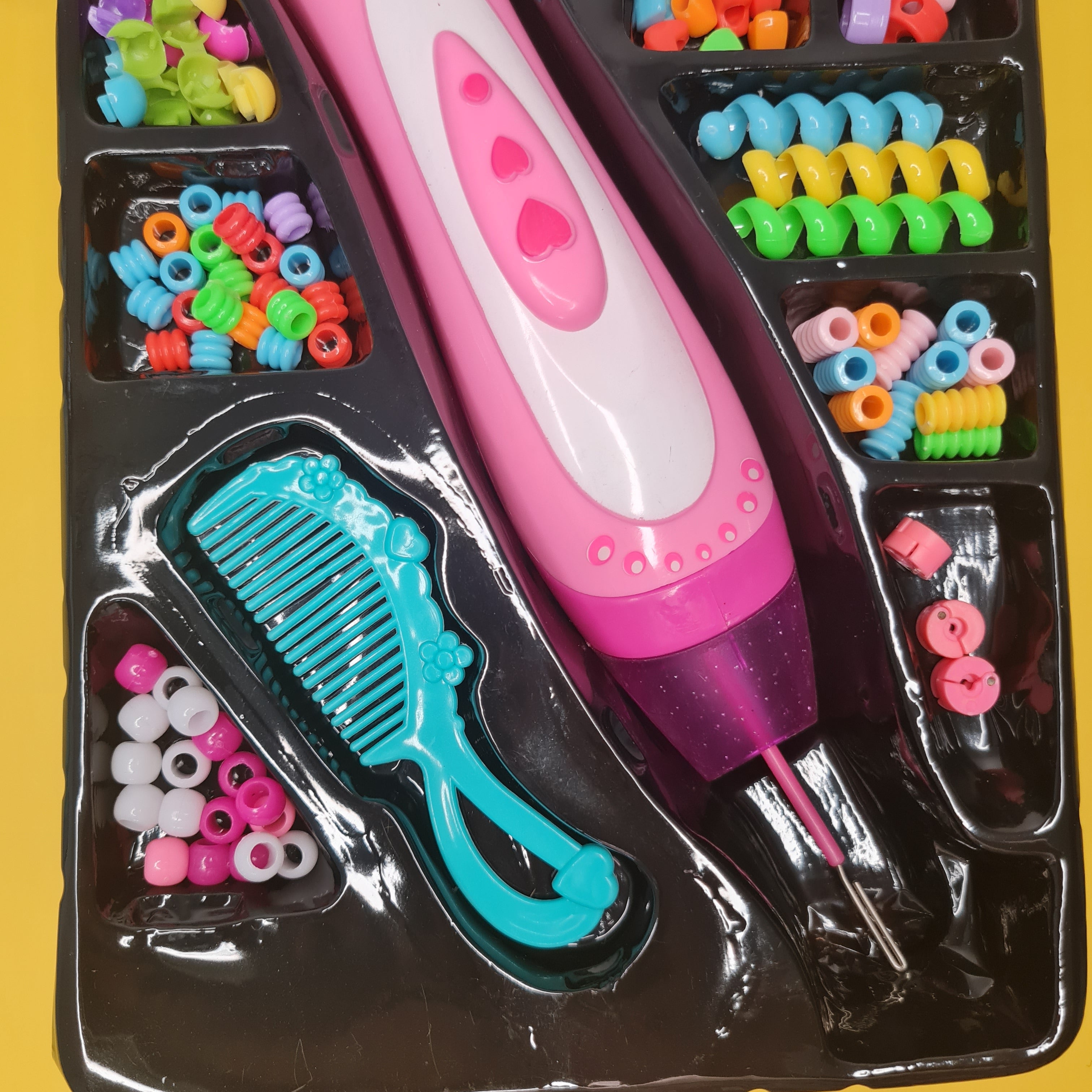 Children's hair styling set with pink brush, blue comb, and colorful beads on a yellow background.